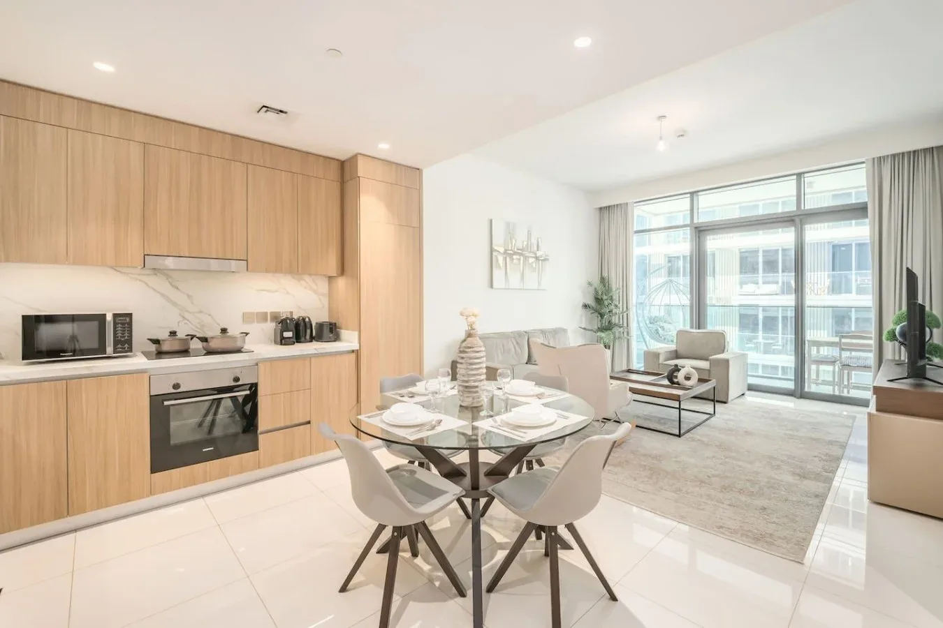 Una sala-comedor de planta abierta con cocina, mesa de comedor y grandes ventanales.