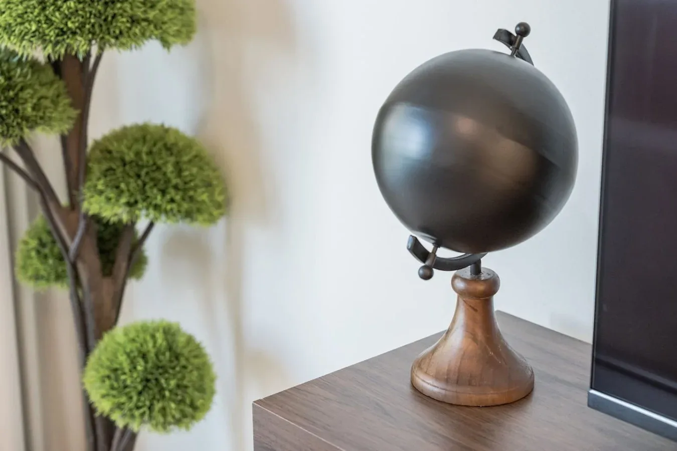 Un globo decorativo está sobre una mesa de madera junto a un topiario en maceta.