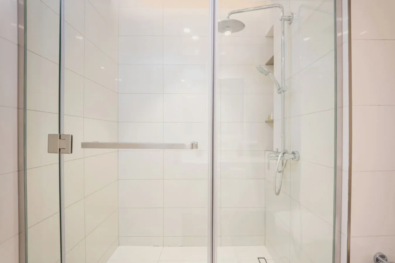 Una ducha de baño con azulejos, paneles de vidrio y un cabezal montado.