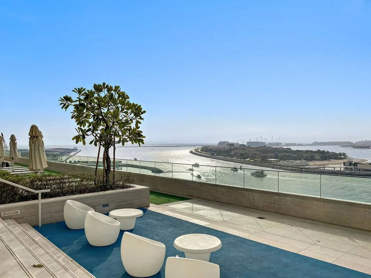 Una terraza en la azotea da al agua, con asientos al aire libre junto a una barandilla de vidrio.