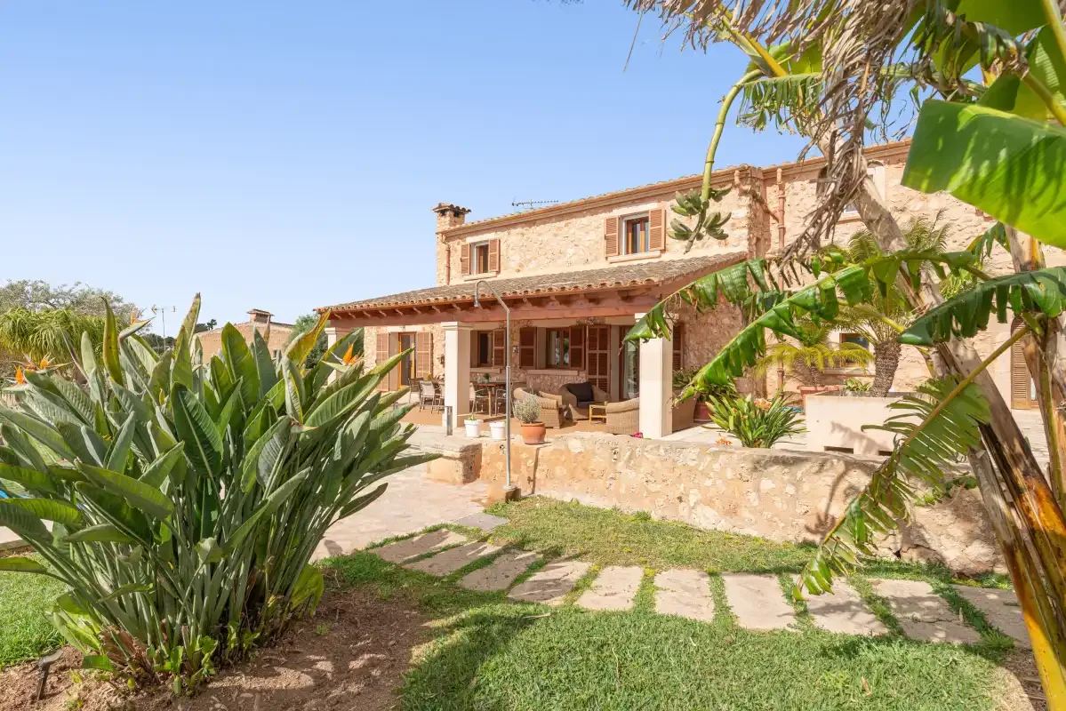 A stone house with a covered patio and a garden in front.