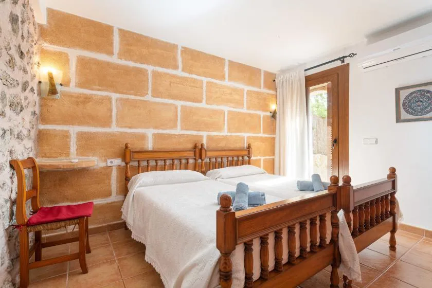 A bedroom with two beds, wooden frames, and a brick-patterned wall.