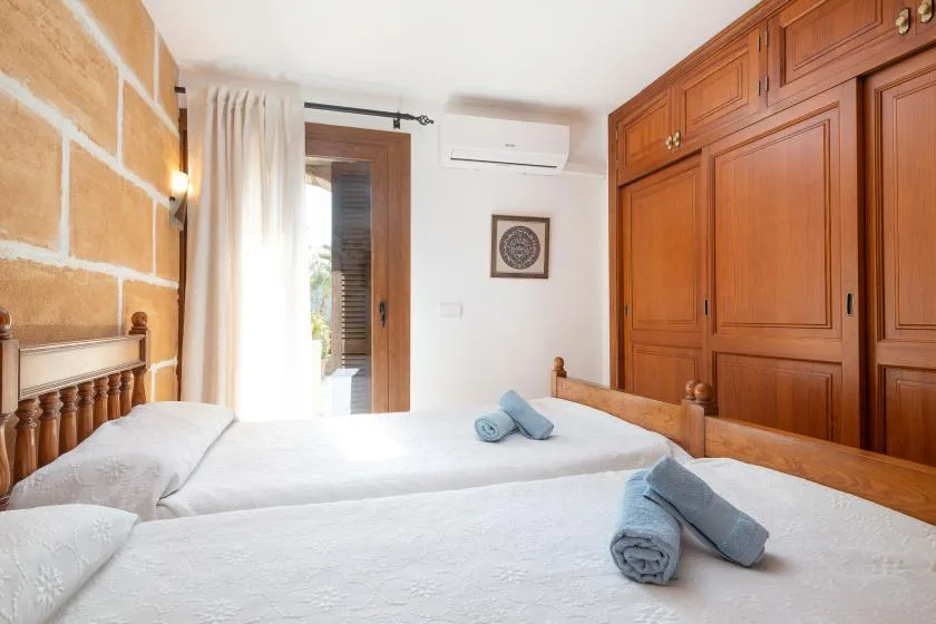 A bedroom with two beds, wooden cabinetry, and a bright doorway.