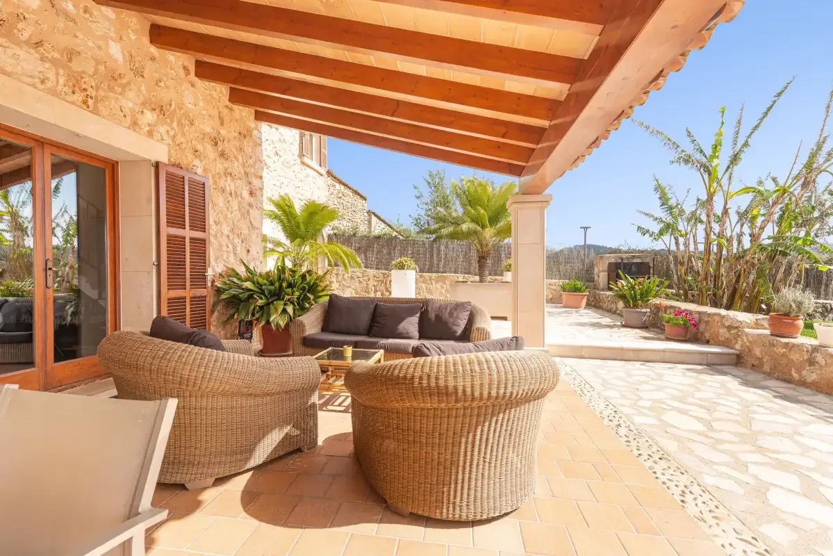 A covered outdoor patio with woven seating and potted plants.