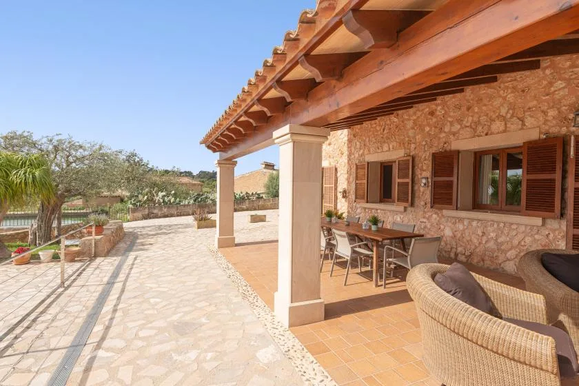 A stone-paved patio beside a stone house, with covered outdoor seating.
