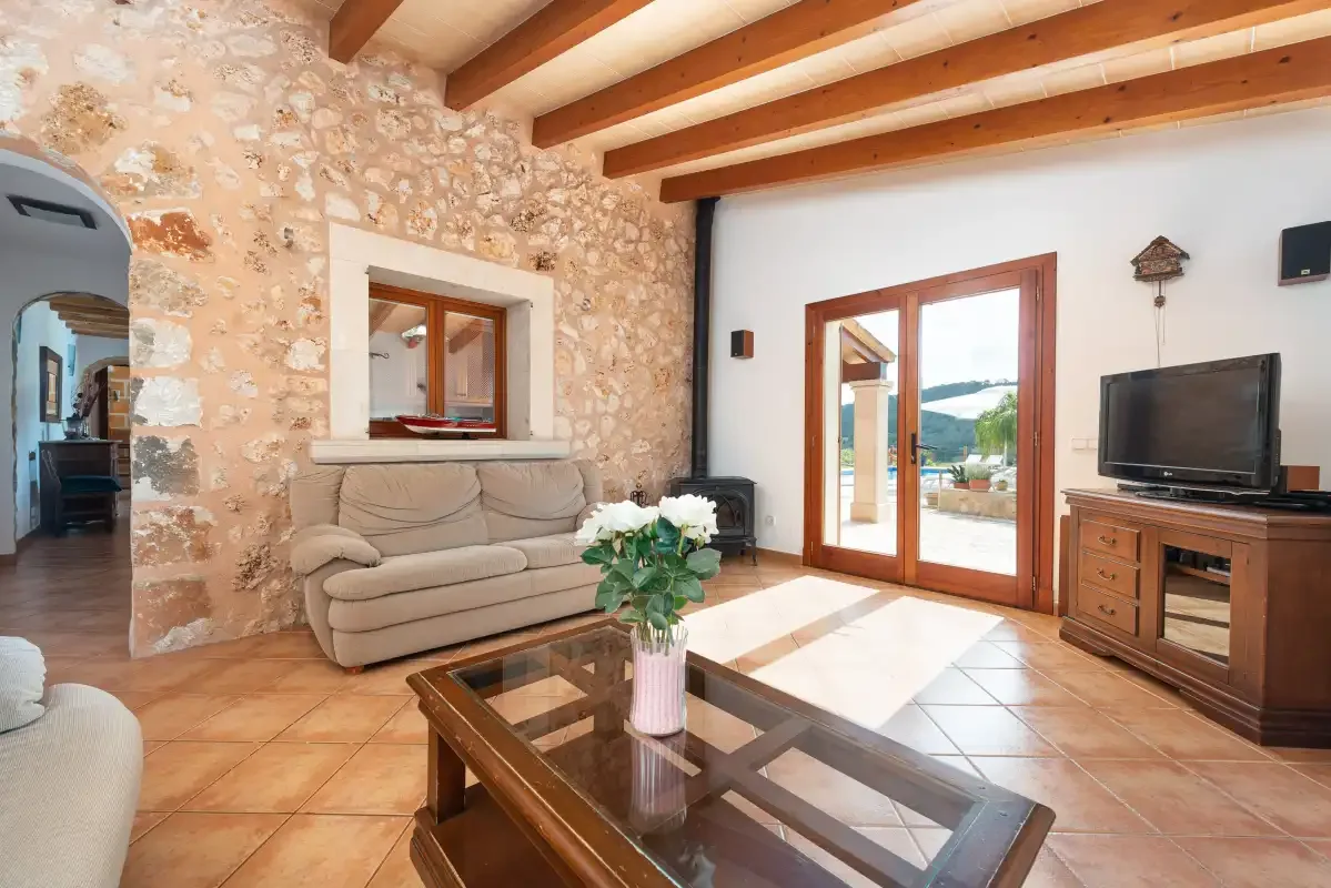 A living room with seating, a glass coffee table, and doors opening onto a patio.