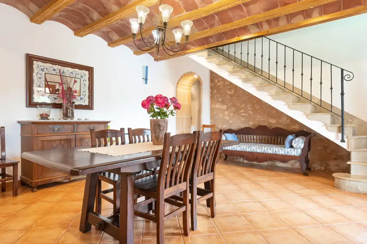 A dining area with a wooden table and seating beneath a staircase.