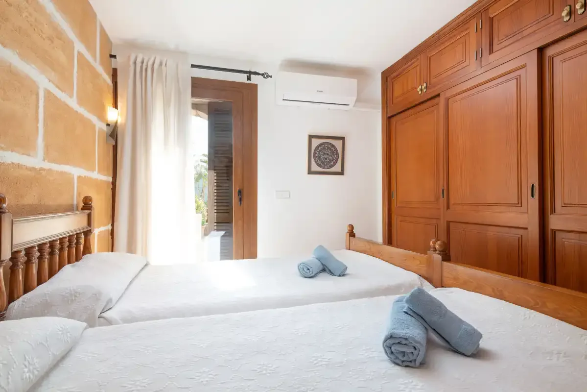 A bedroom with a large wooden wardrobe and neatly made beds.