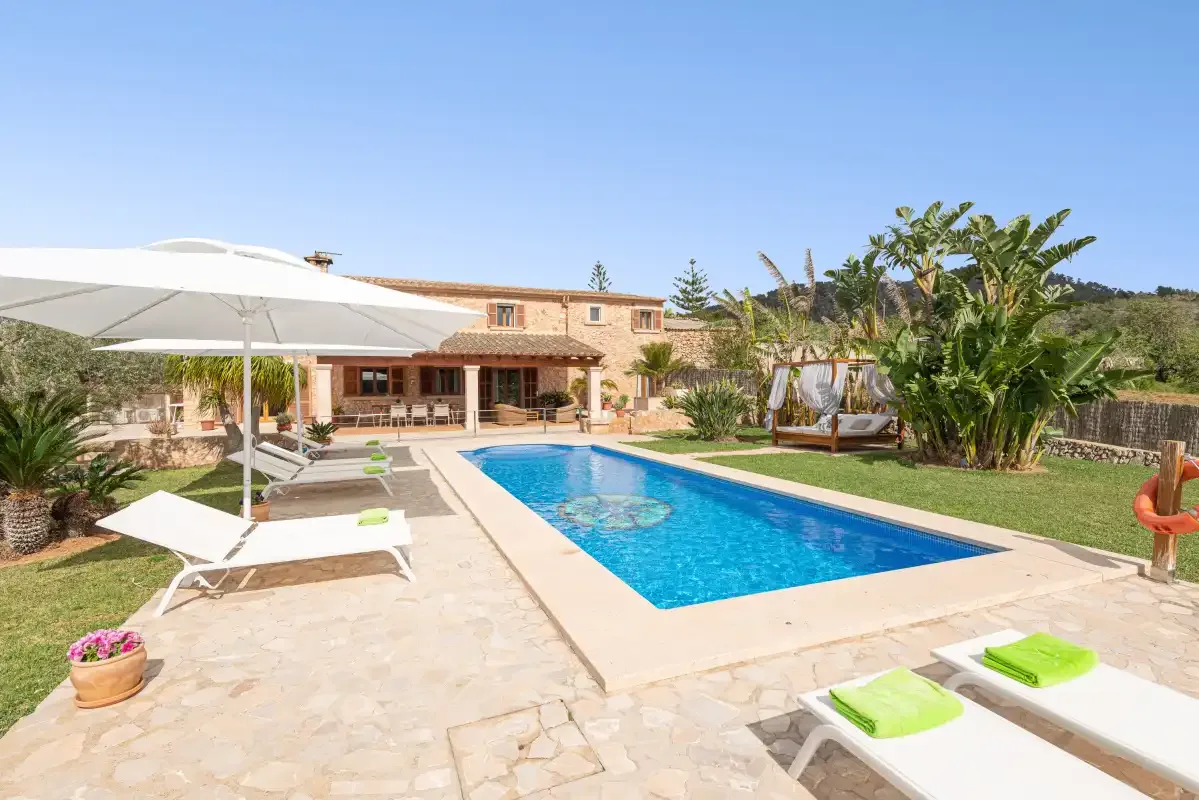 An outdoor swimming pool sits beside a stone-paved patio and loungers.