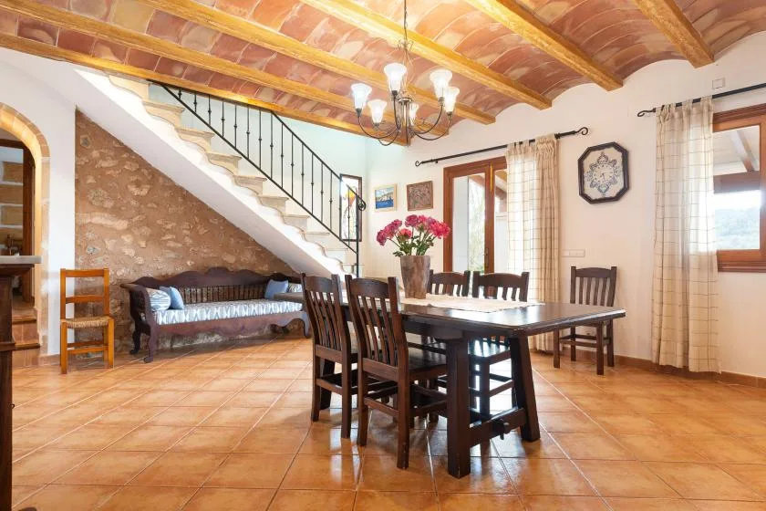 A dining area with a wooden table and chairs beneath exposed ceiling beams.