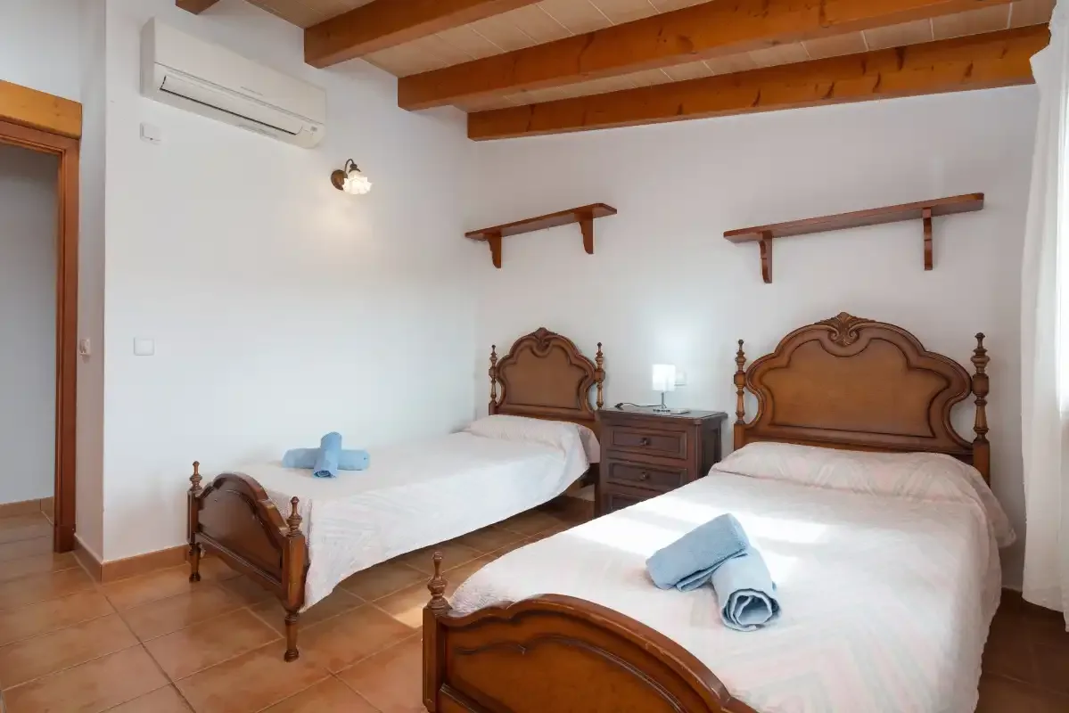 A bedroom with two beds and exposed wooden ceiling beams.