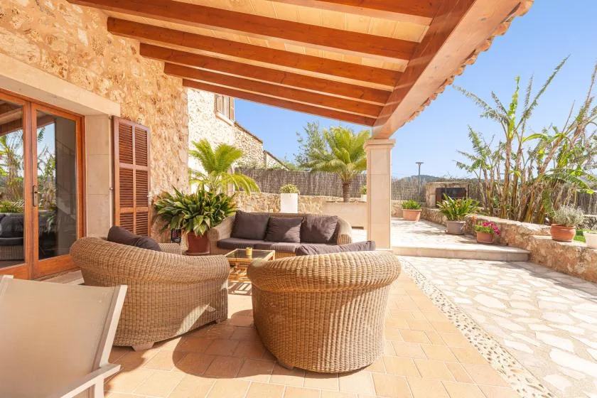 A covered outdoor seating area opens onto a sunny stone-paved terrace.