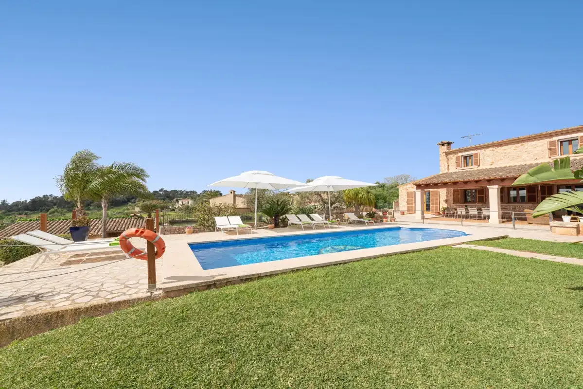 A swimming pool beside a stone-paved patio and a house.