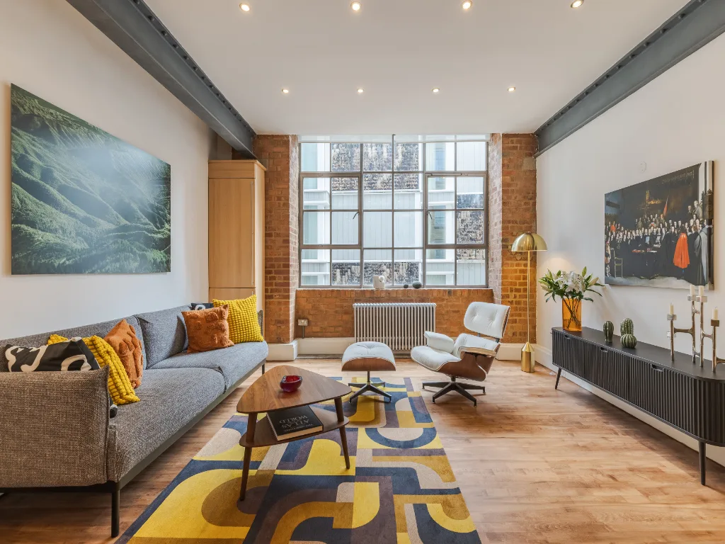A living room with seating around a coffee table on a colorful rug.