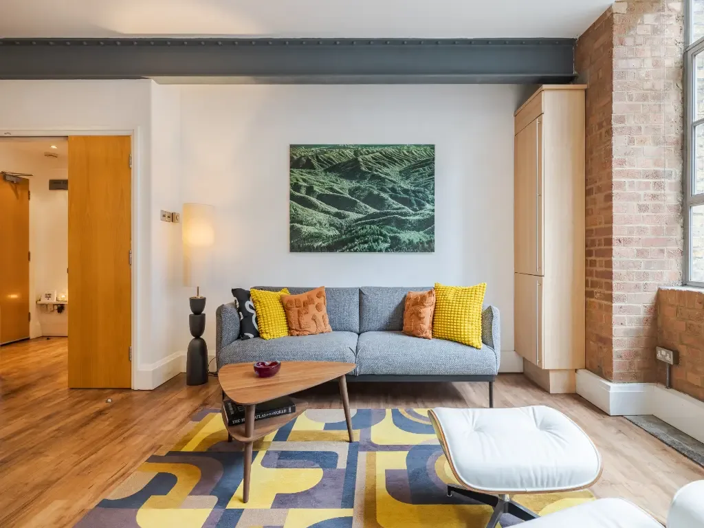 Una sala de estar con asientos, una mesa baja y una alfombra colorida.