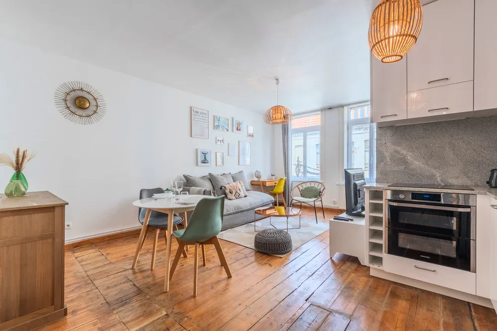 A bright living room with seating, a dining table, and an open kitchen.