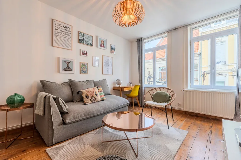 A bright living room with a gray sofa, coffee table, and large windows.