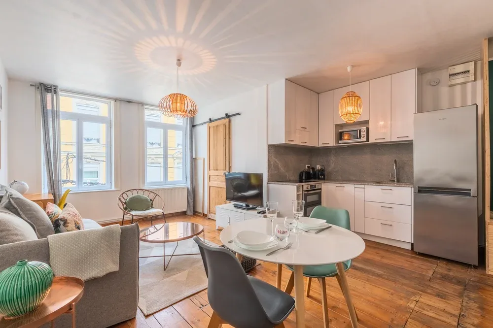 A bright open-plan living and dining area with a compact kitchen and large windows.