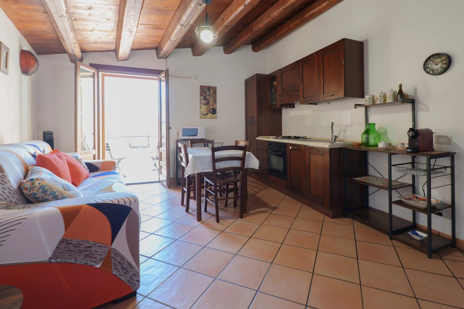Una sala con comedor y una cocina pequeña bajo un techo de madera.