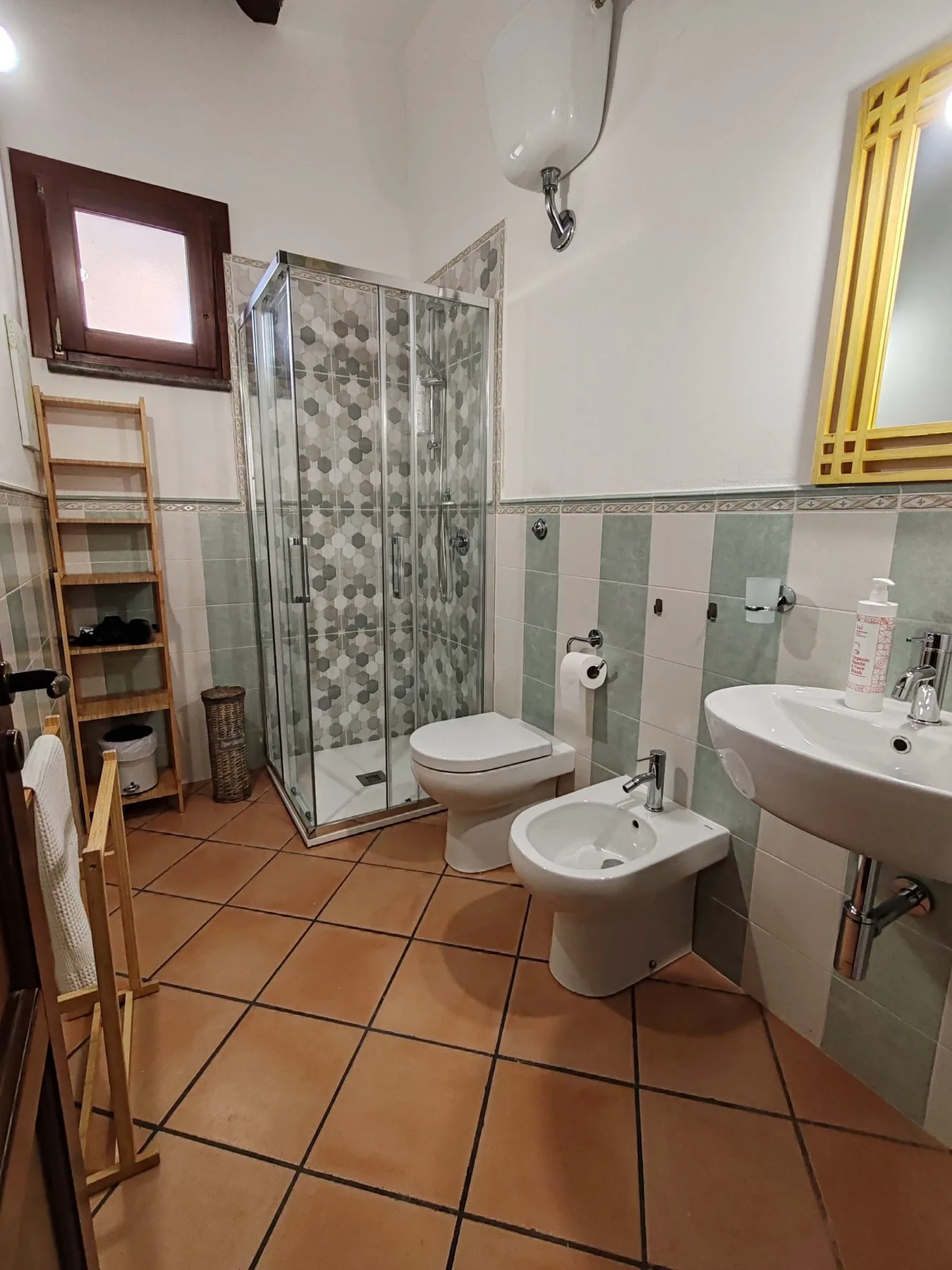 Un baño con azulejos, ducha de vidrio, inodoro, bidé y lavabo.