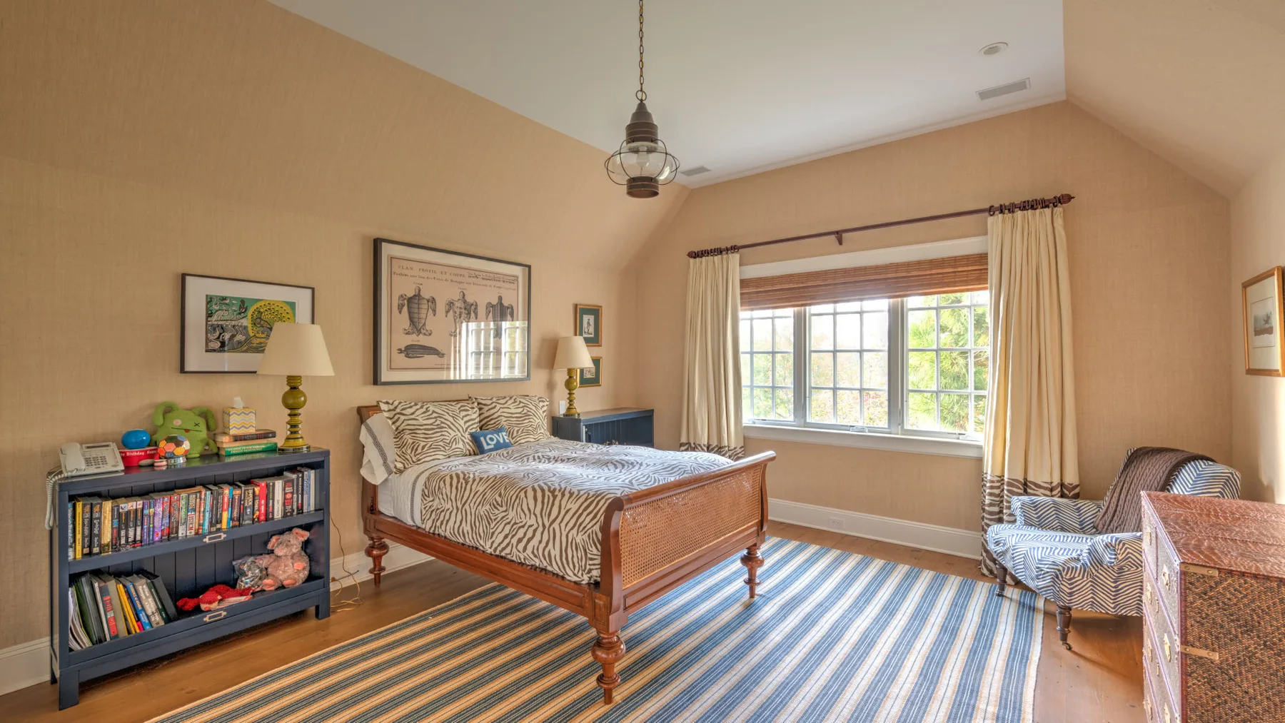 Un dormitorio con una cama de madera, ropa de cama a rayas y una ventana grande.