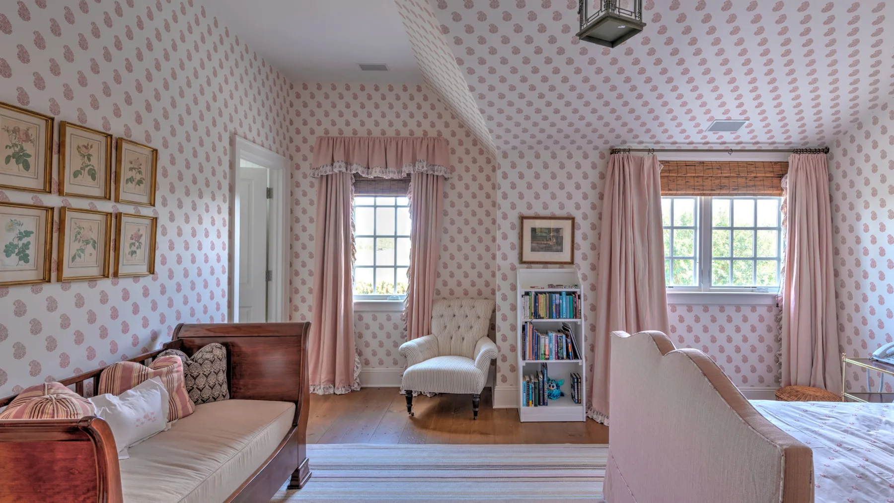 Una sala de estar con papel tapiz estampado, ventanas con cortinas y asientos tapizados.