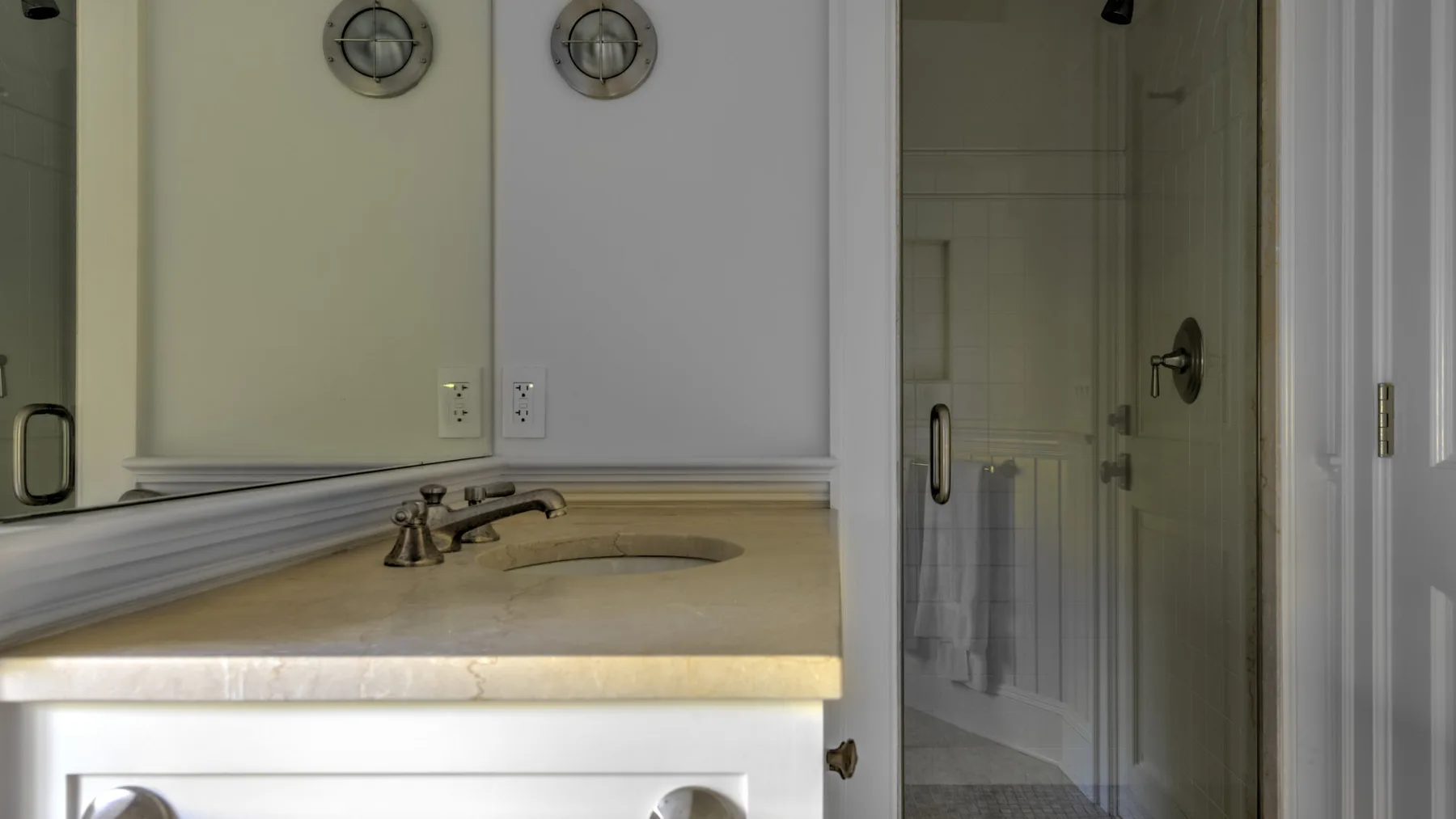 Un tocador de baño con lavabo y una puerta hacia la zona de la ducha.