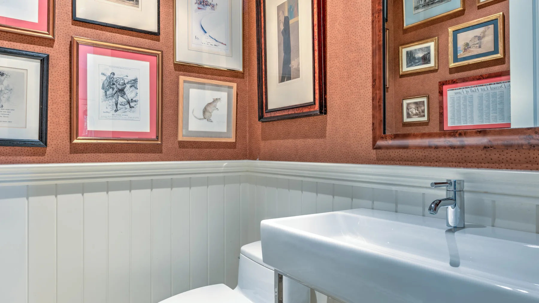 Un lavabo de baño está bajo cuadros enmarcados en las paredes.