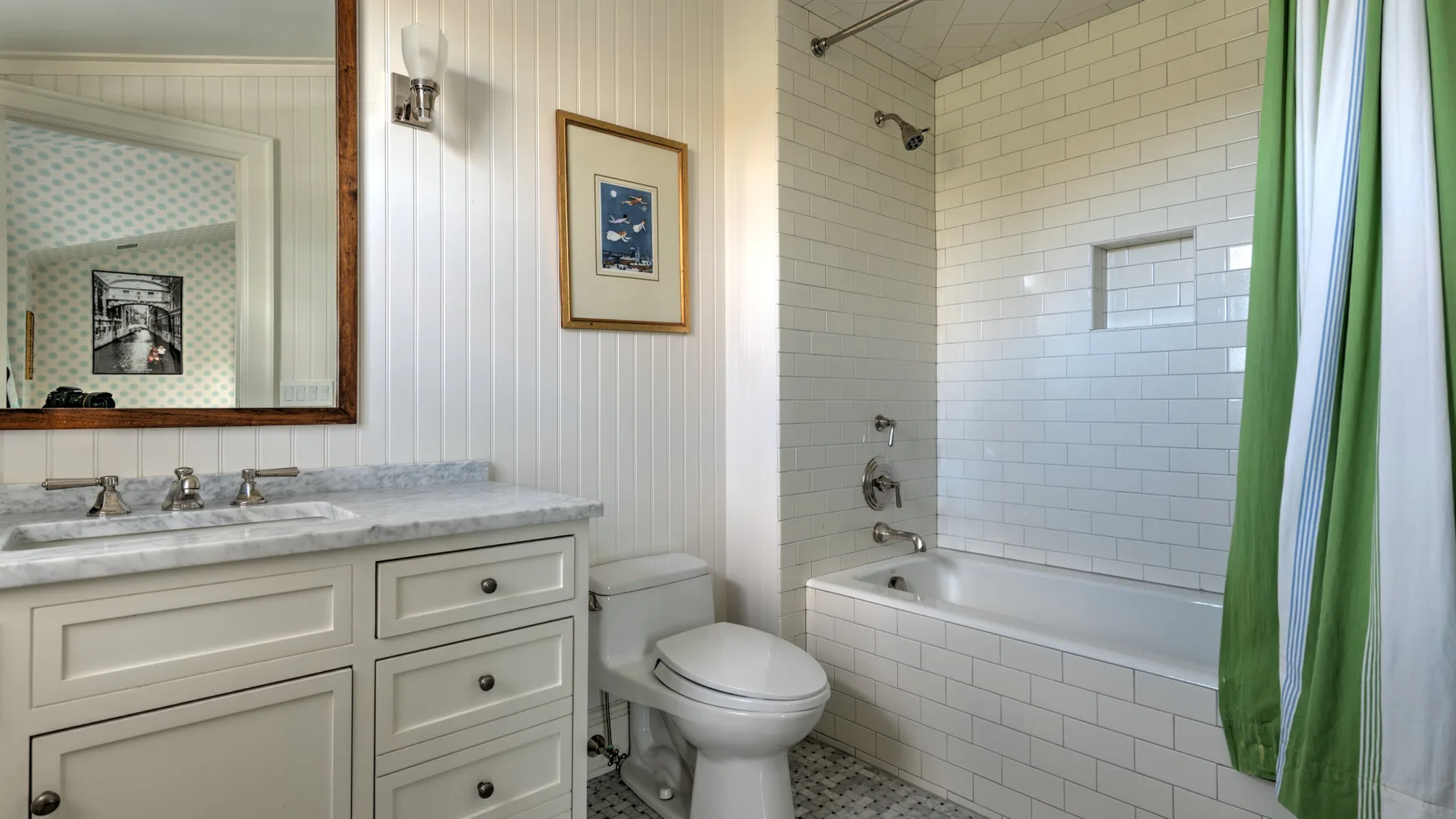 Un baño con lavabo, inodoro y bañera detrás de una cortina verde.