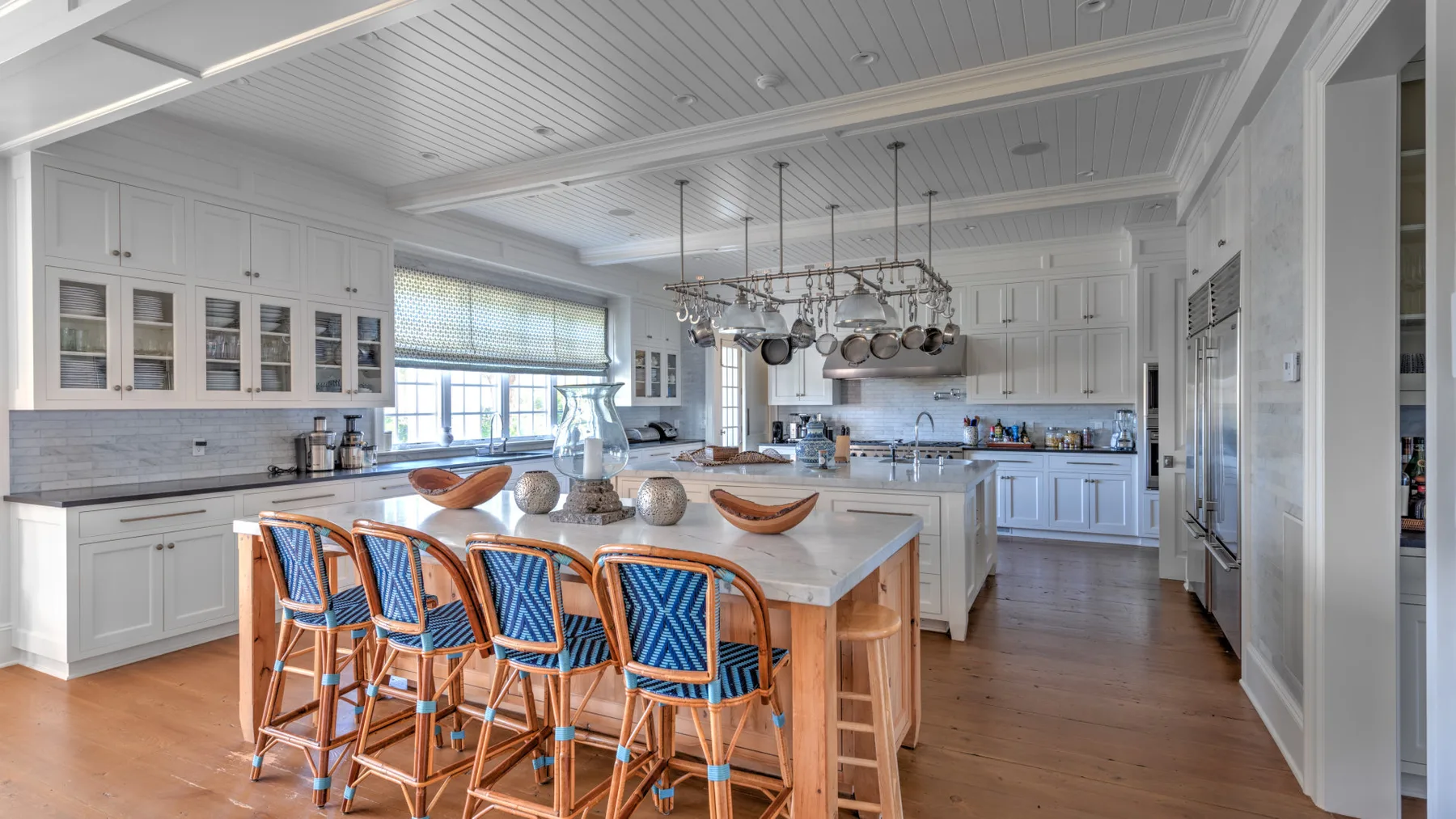 Una cocina luminosa con una isla grande y asientos con respaldos azules.