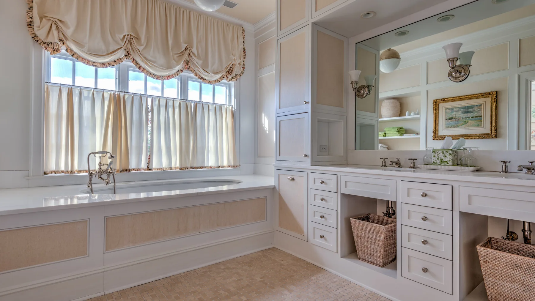 Un baño luminoso cuenta con un tocador largo, un espejo grande y ventanas con cortinas.