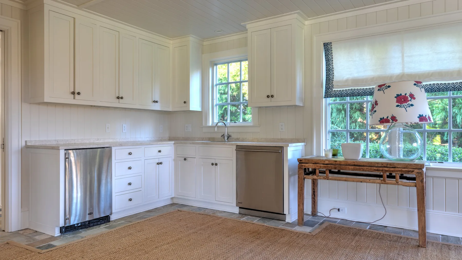 Una cocina luminosa con gabinetes blancos, una estufa de acero inoxidable y ventanas.