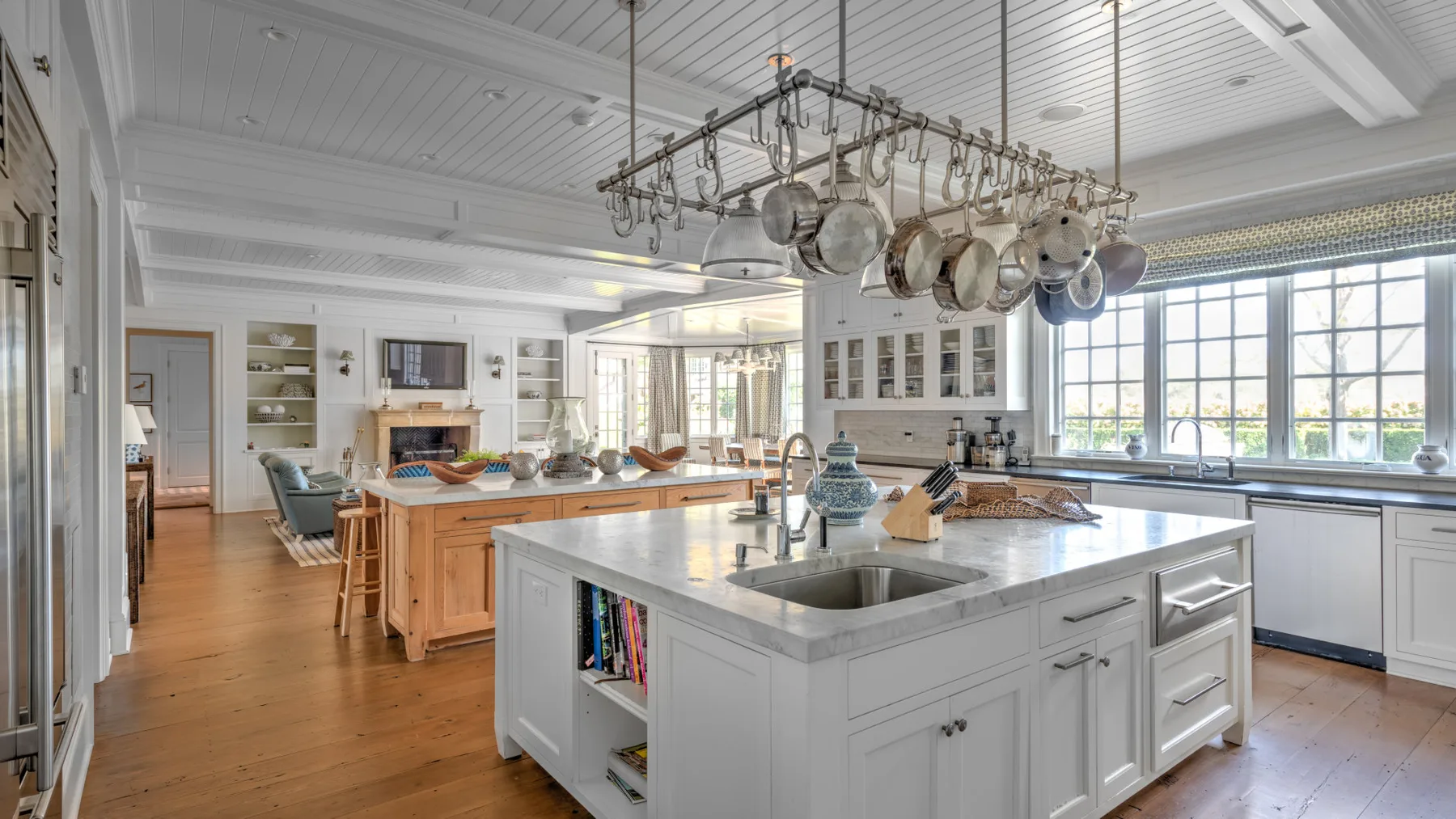 Una cocina luminosa con una isla grande y utensilios colgantes.
