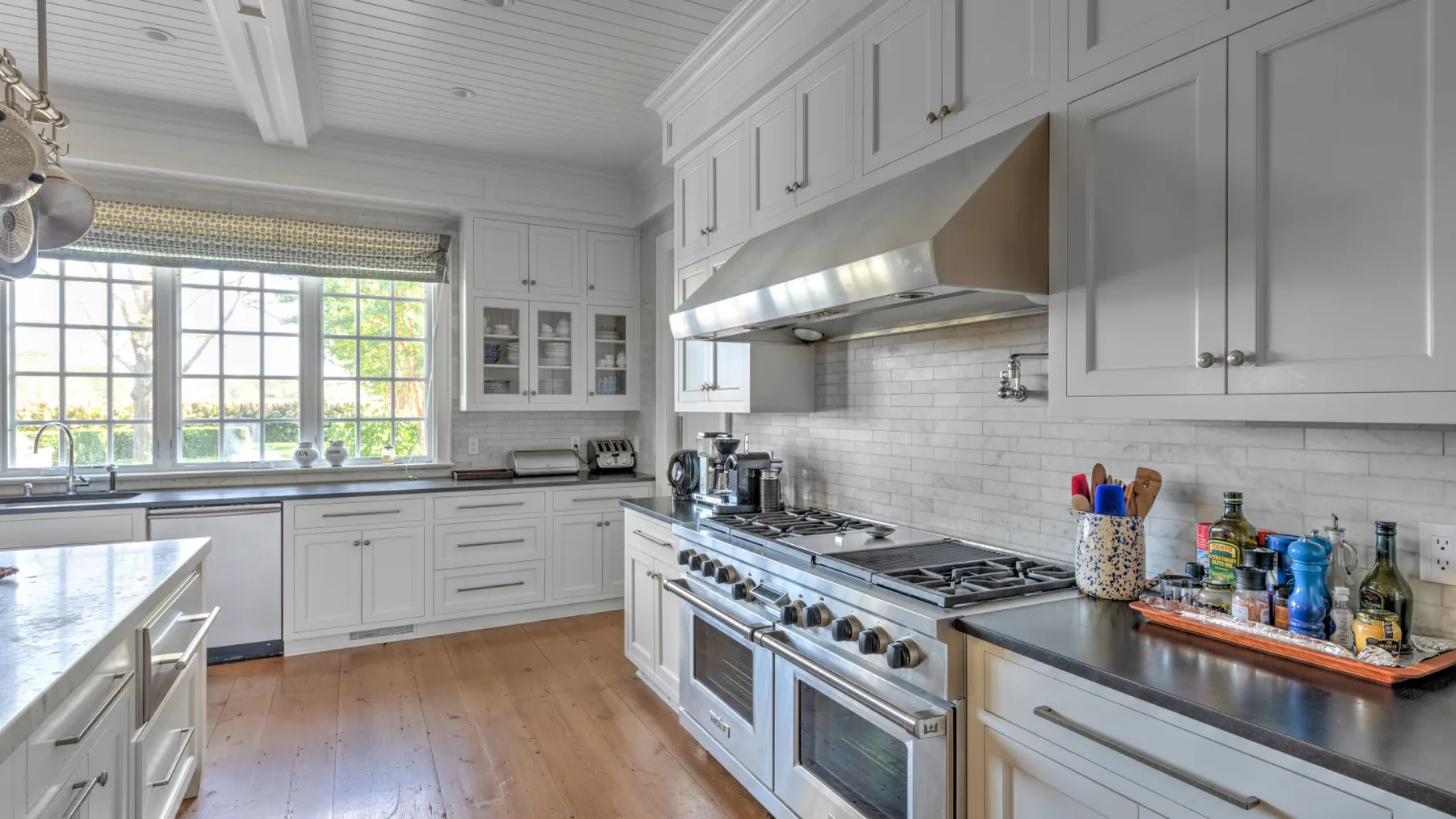 Una cocina luminosa con gabinetes blancos, una estufa amplia y una ventana grande.