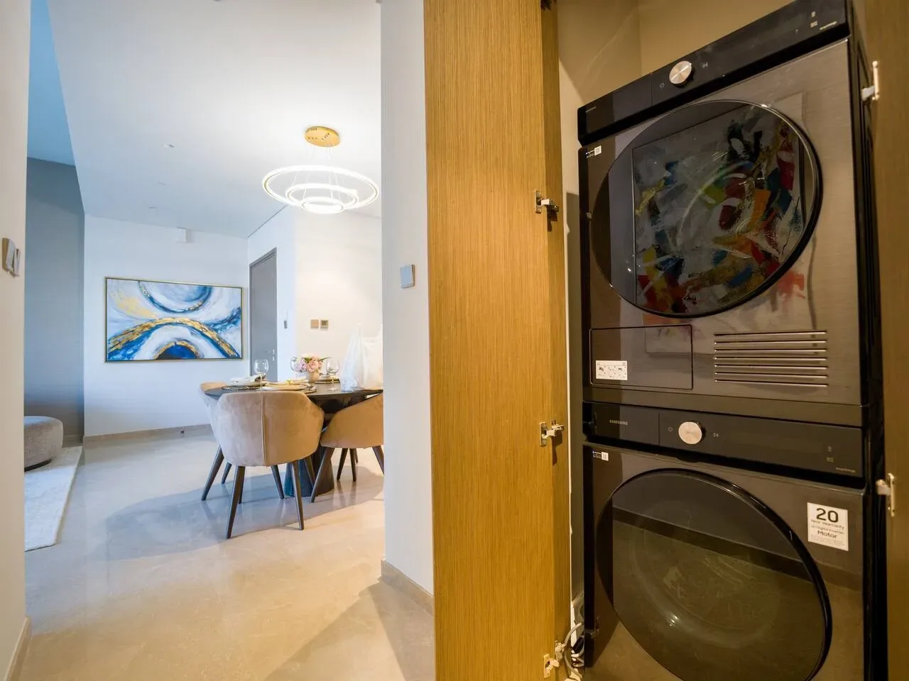 A laundry area with stacked appliances opens onto a dining space.