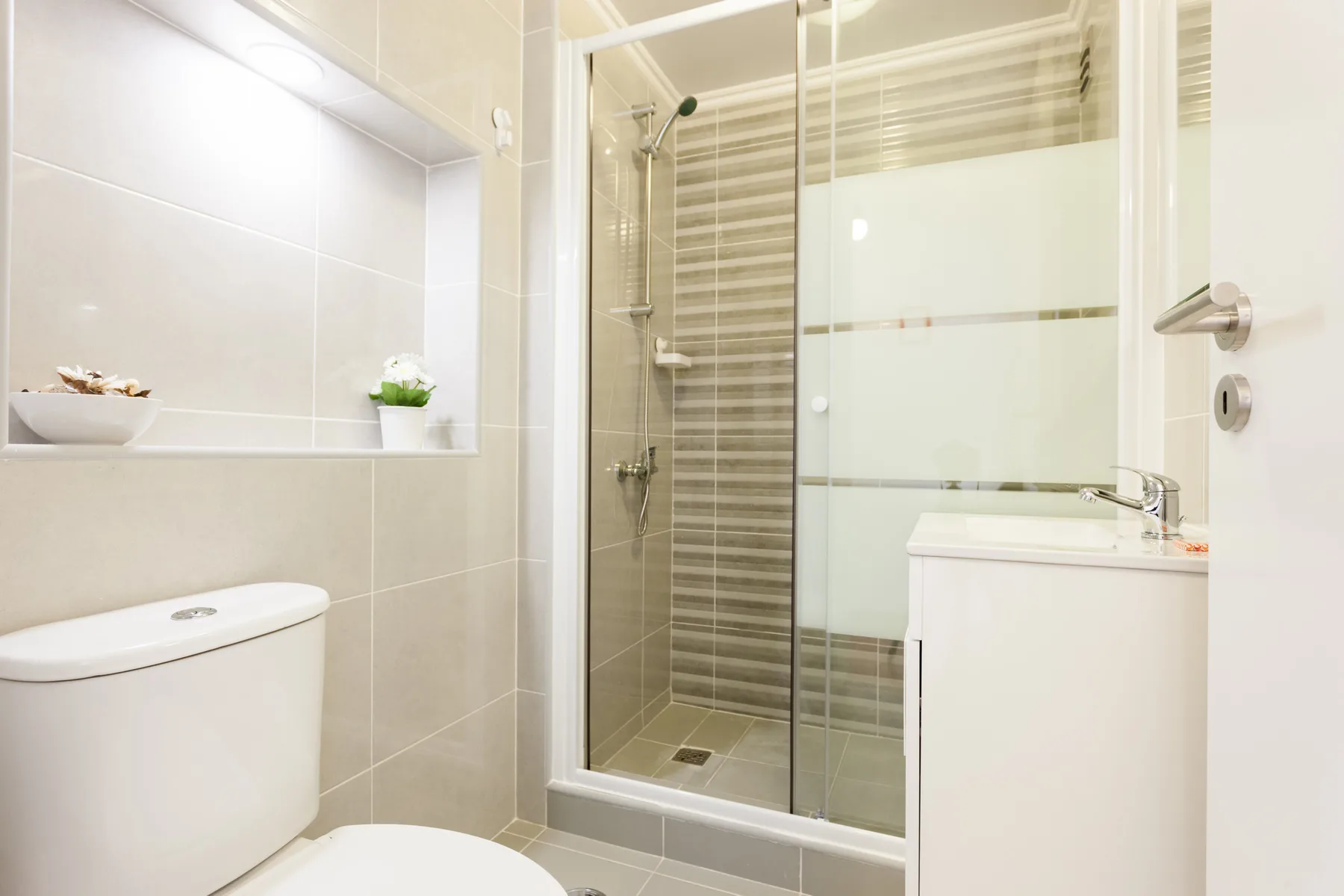 A tiled bathroom with a glass shower and a sink.