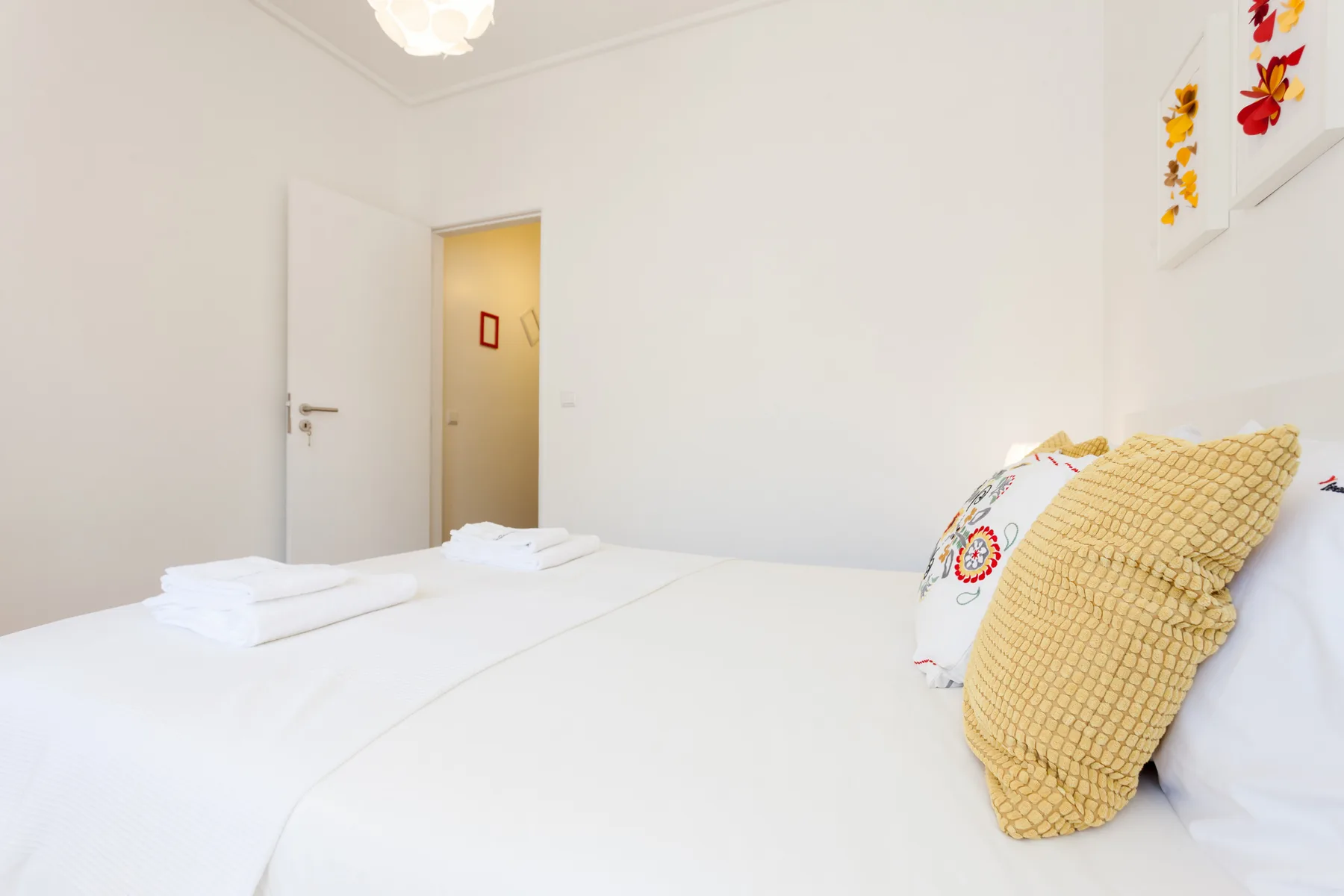 Un dormitorio con ropa de cama blanca y cojines decorativos.