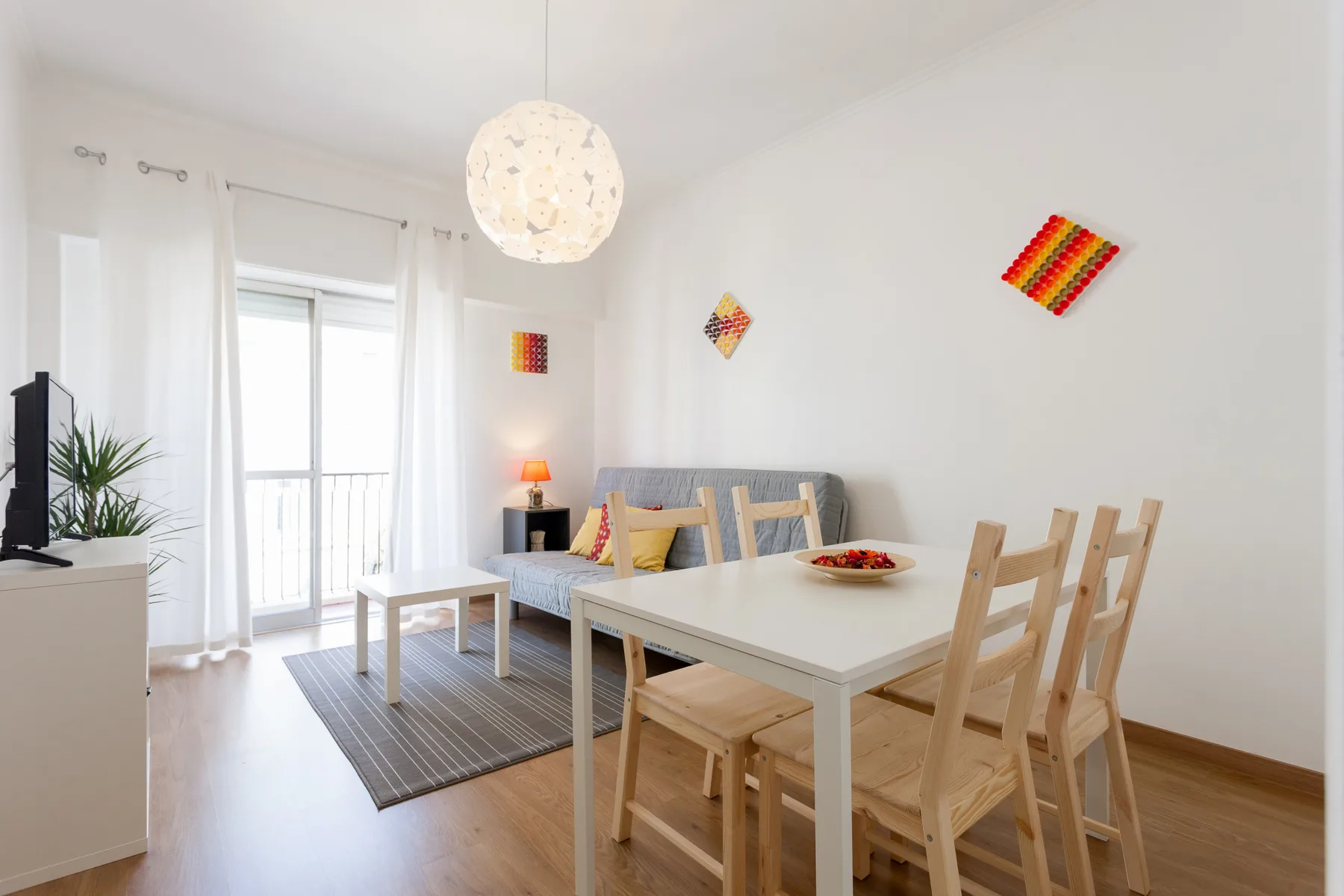 Una luminosa zona de comedor y estar con una mesa de madera y asientos.