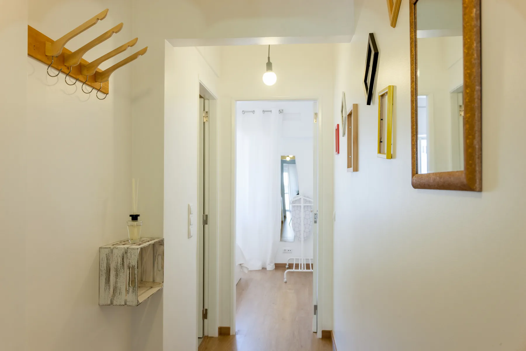 A bright hallway leads to a room with a mirror and light-colored floor.