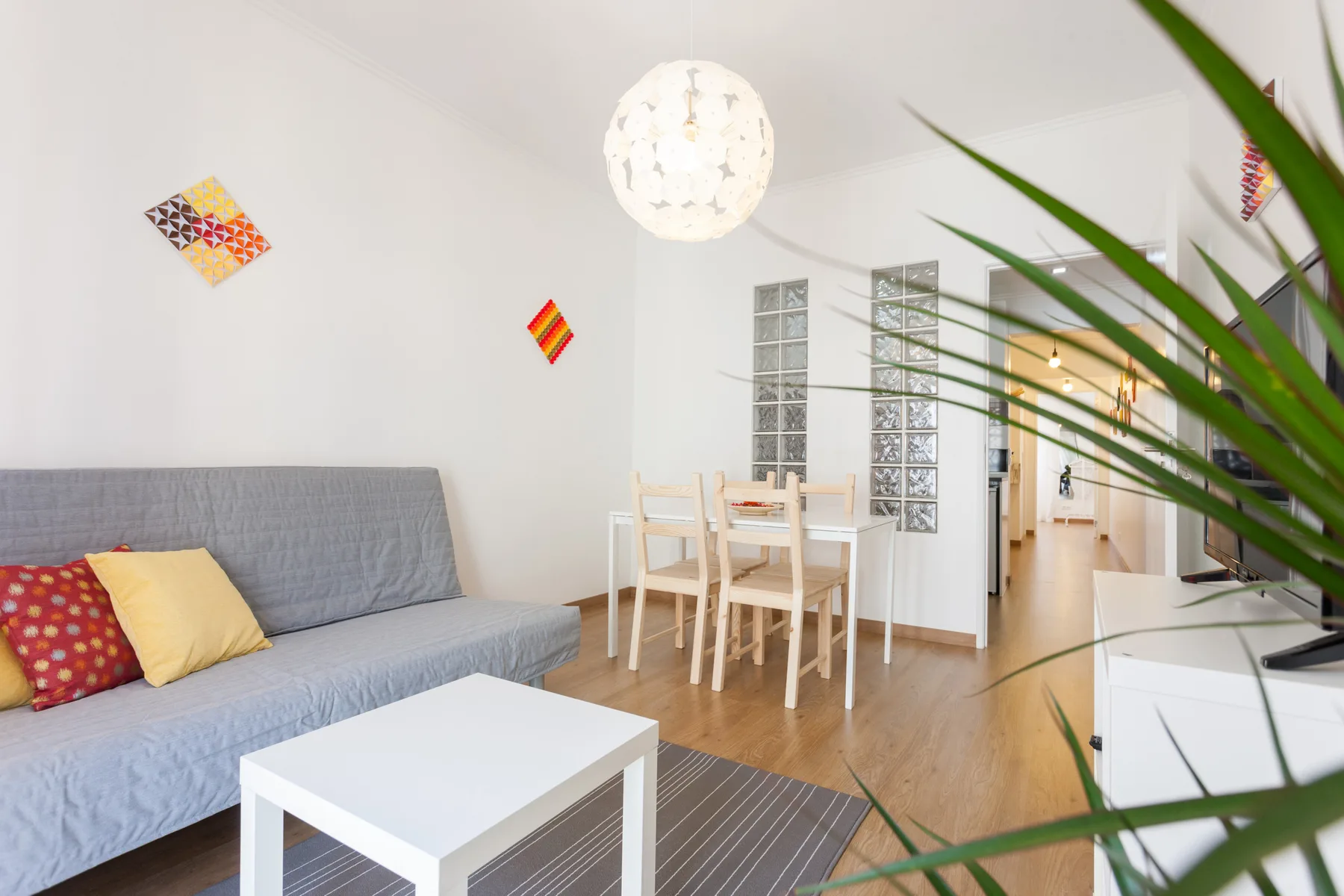 Una luminosa sala de estar y comedor con asientos, una mesa y una planta frondosa.