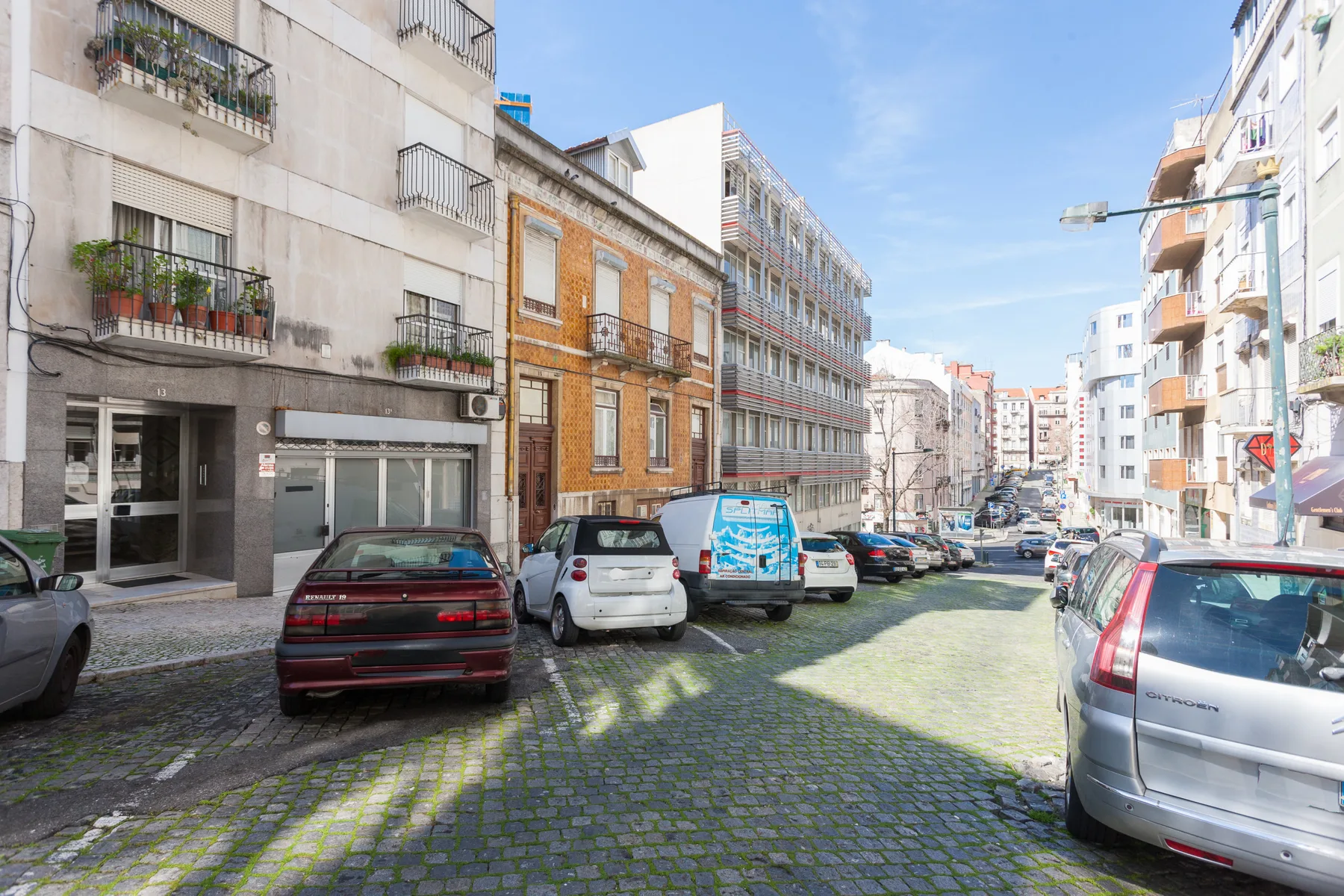 Una calle adoquinada con edificios de apartamentos y coches estacionados.