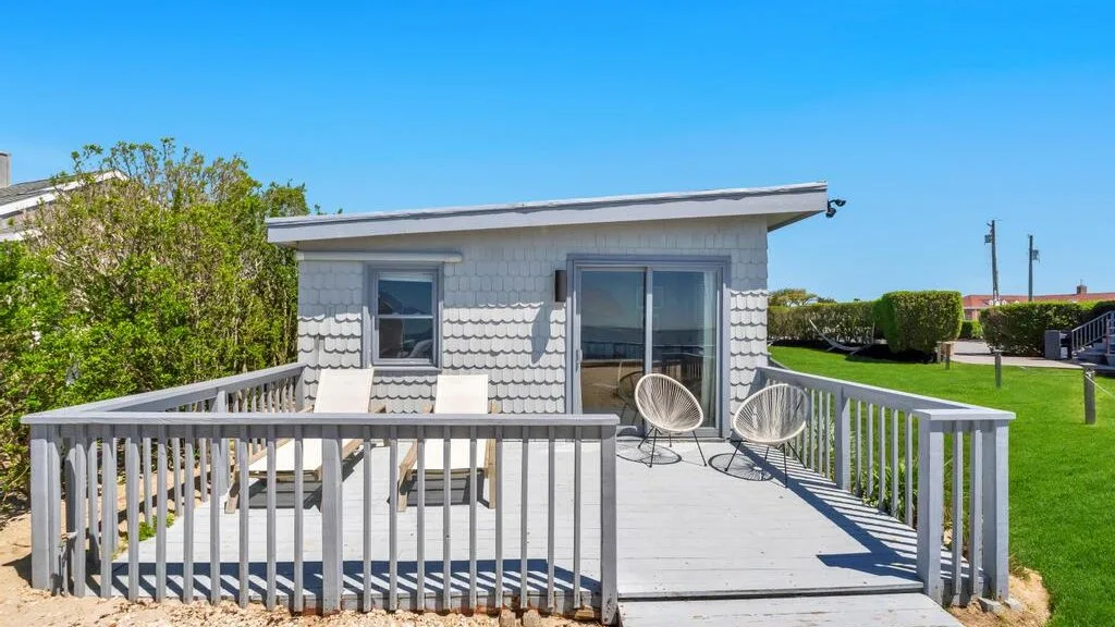 A raised outdoor deck with railings, seating, and sliding glass doors.