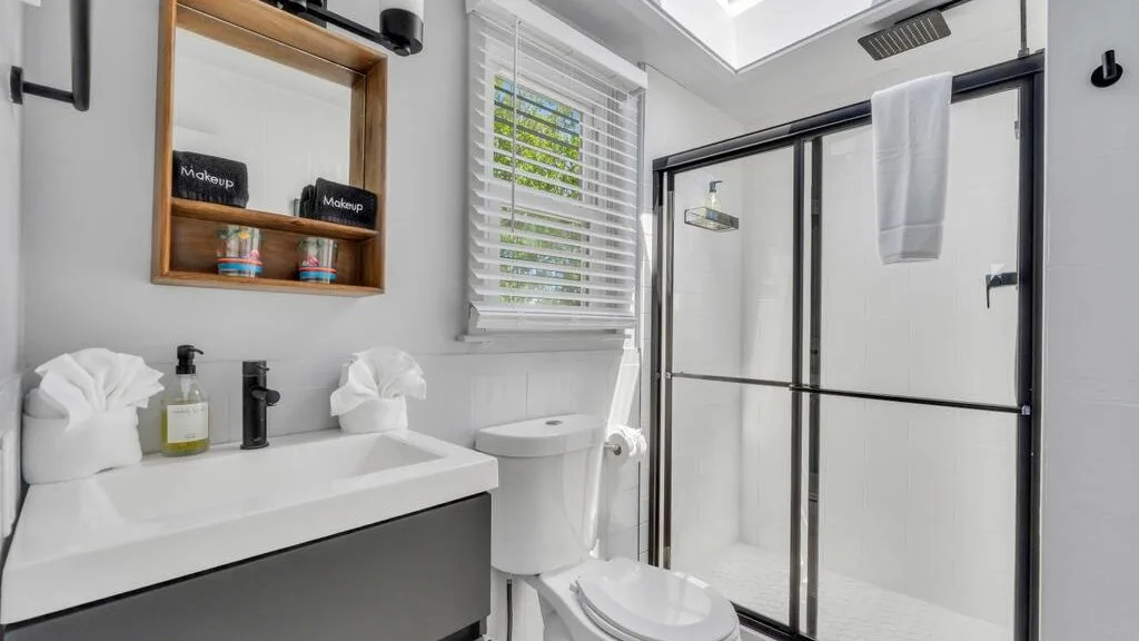 A bright bathroom with a vanity, toilet, and glass shower.