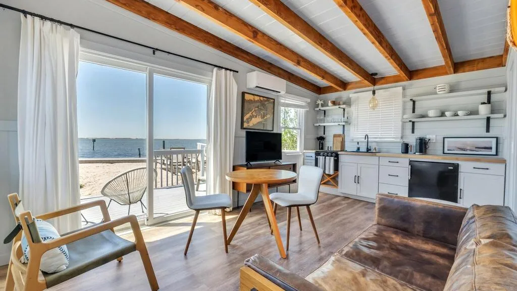 A bright open-plan living and dining area with a kitchen and ocean views through sliding glass doors.