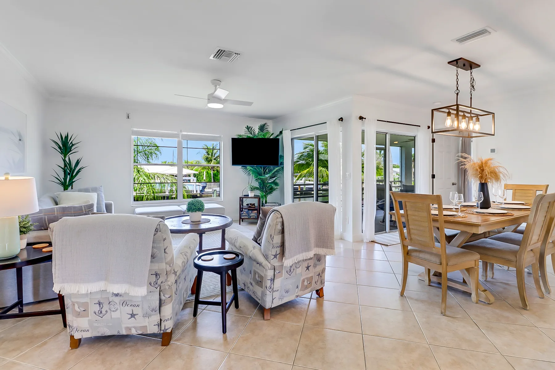 A bright living and dining area with seating, a television, and a wooden dining table.