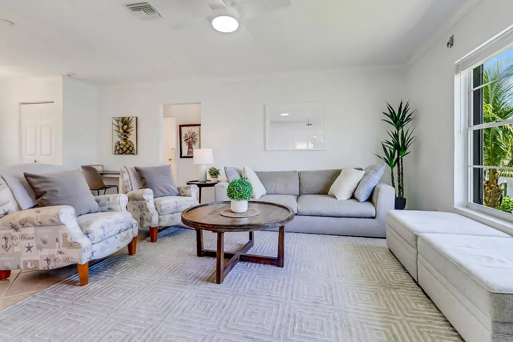 A bright living room with seating around a coffee table and a large window.