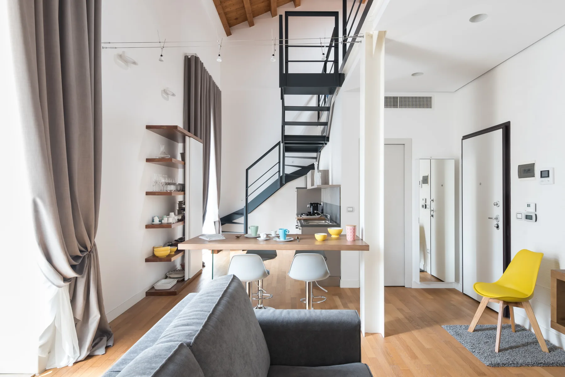 Una luminosa sala de estar de planta abierta con barra de comedor y escalera.