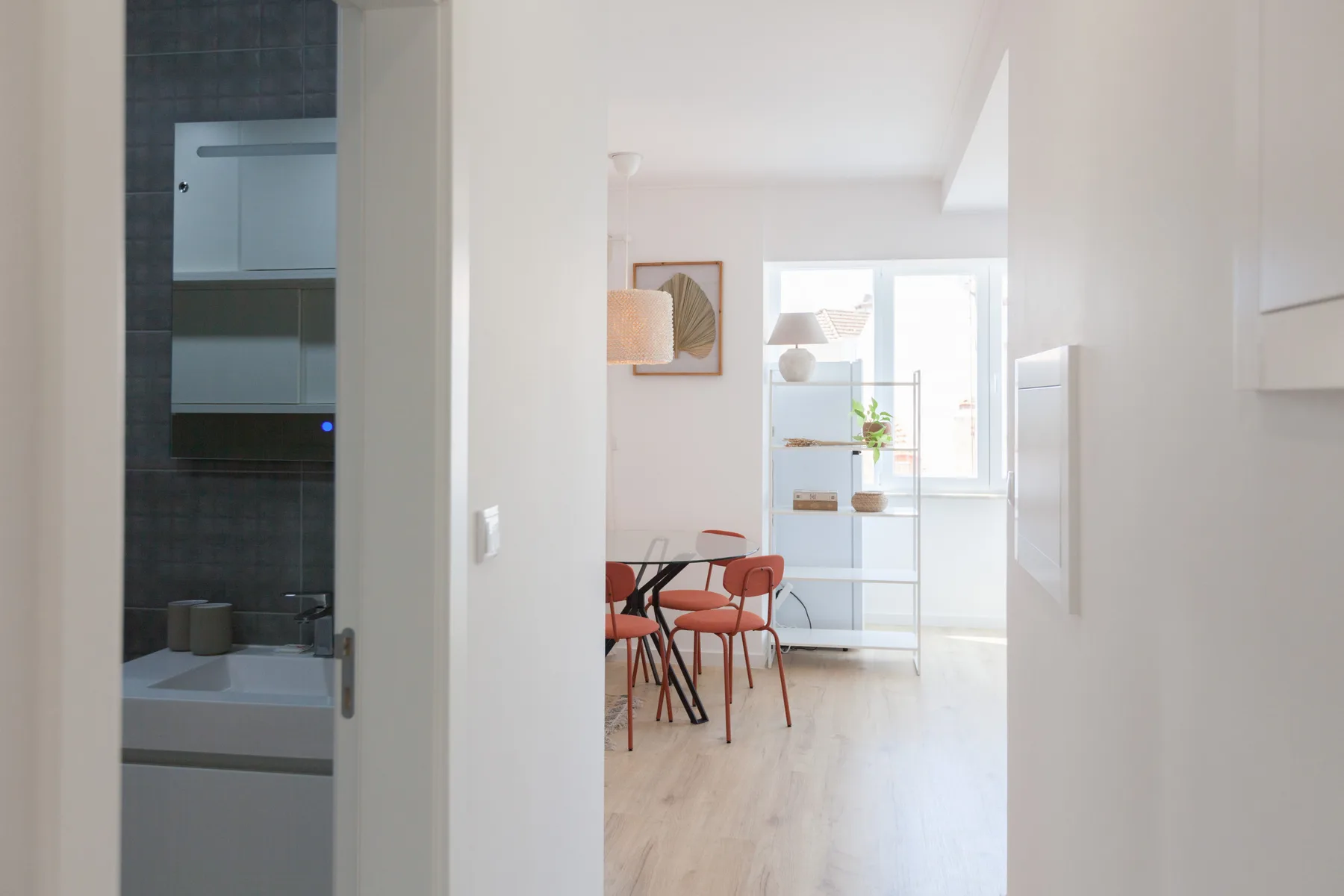 A bright dining area with a table and seating beside a shelving unit.