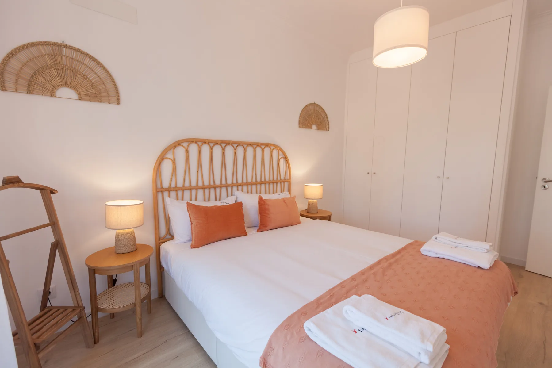 A bedroom with a bed, bedside tables, and a white wardrobe.
