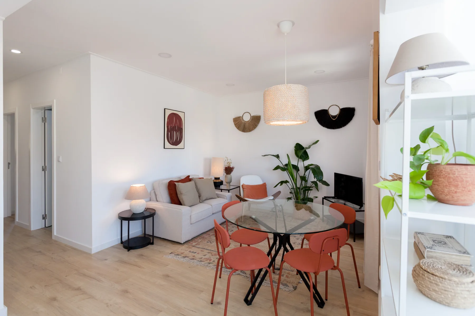 A bright living and dining area with seating, a glass table, and plants.